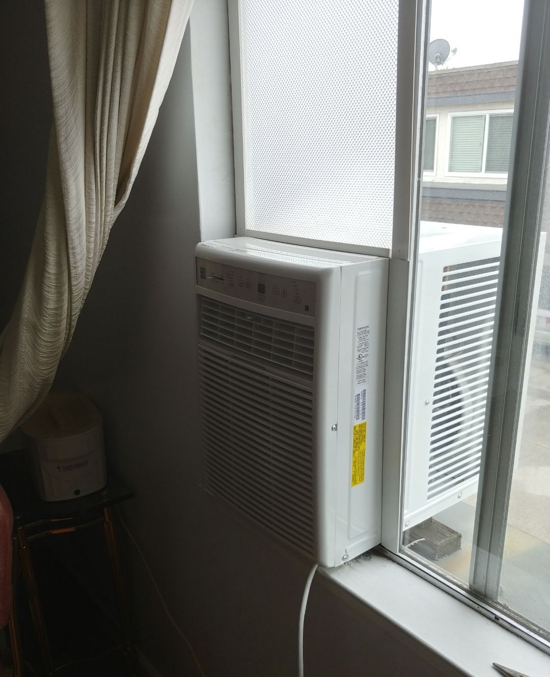 A window air conditioner is attached to the side of a window.