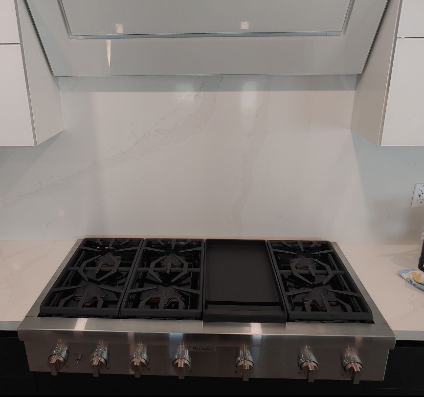 A stainless steel stove top oven with a hood above it