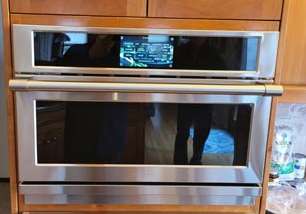 A stainless steel oven is sitting on top of a wooden cabinet in a kitchen.