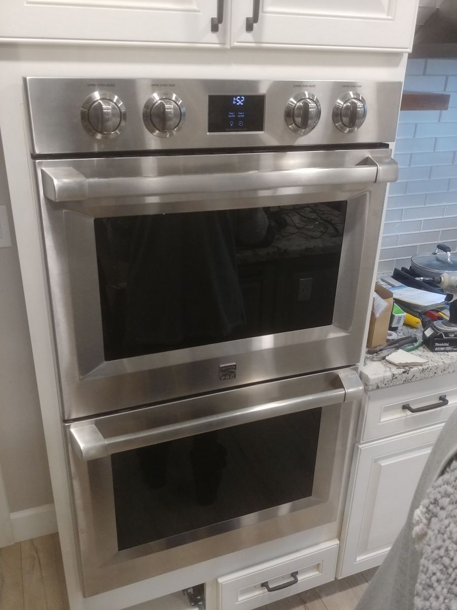 A stainless steel double oven is sitting on top of a white cabinet in a kitchen.