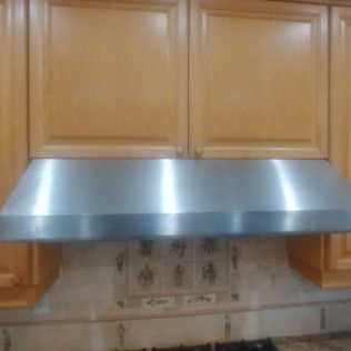 stainless range hood in brown cabinet