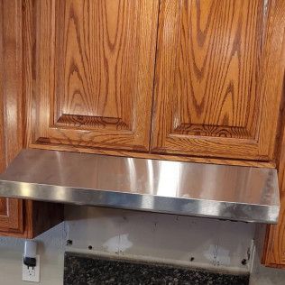 stainless range hood in wooden cabinet
