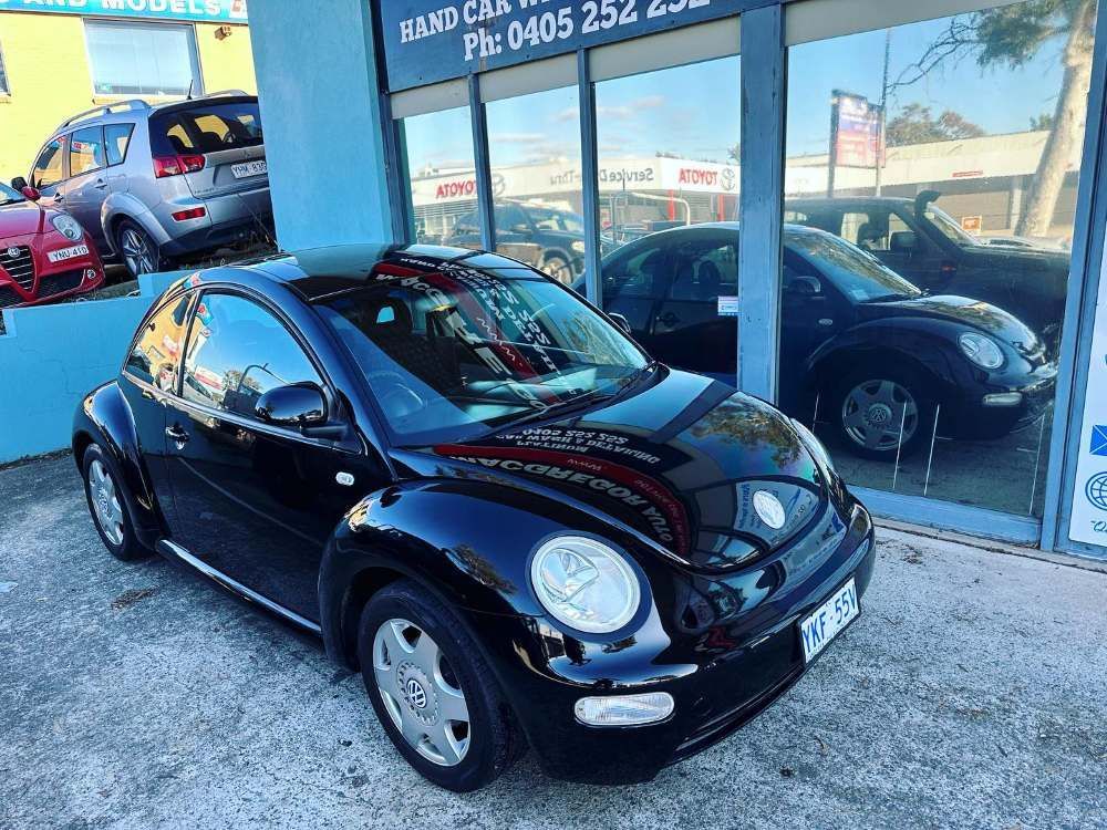 A Black Volkswagen Beetle is Parked in Front of a Car Dealership — Platinum Hand Car Wash & Detailing in Belconnen, ACT