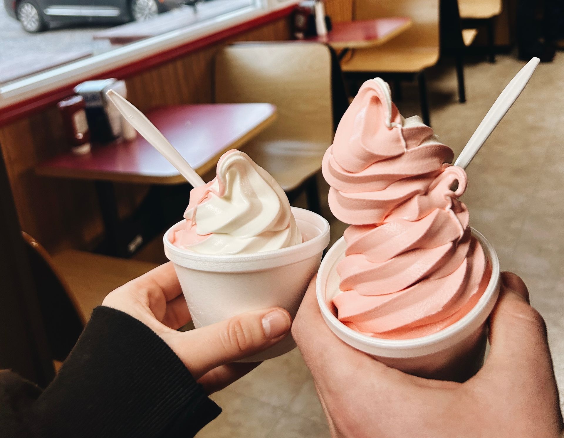 A person is holding two cups of ice cream in their hands.