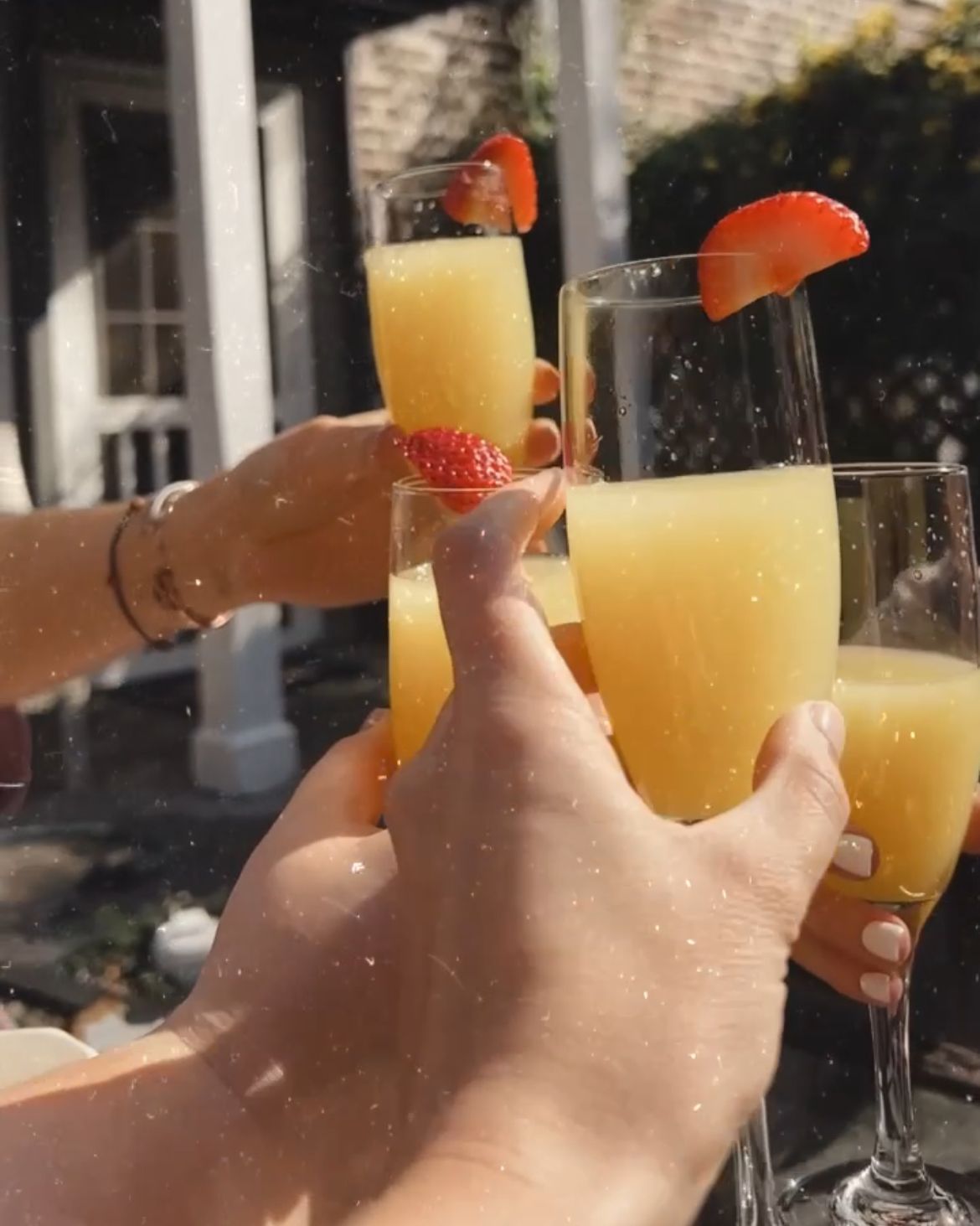 A person is holding a glass of orange juice with strawberries on top.