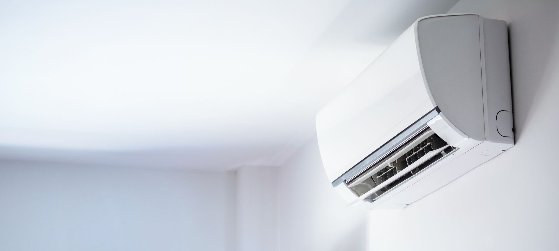 White wall-mounted air conditioner near the ceiling in a bright room