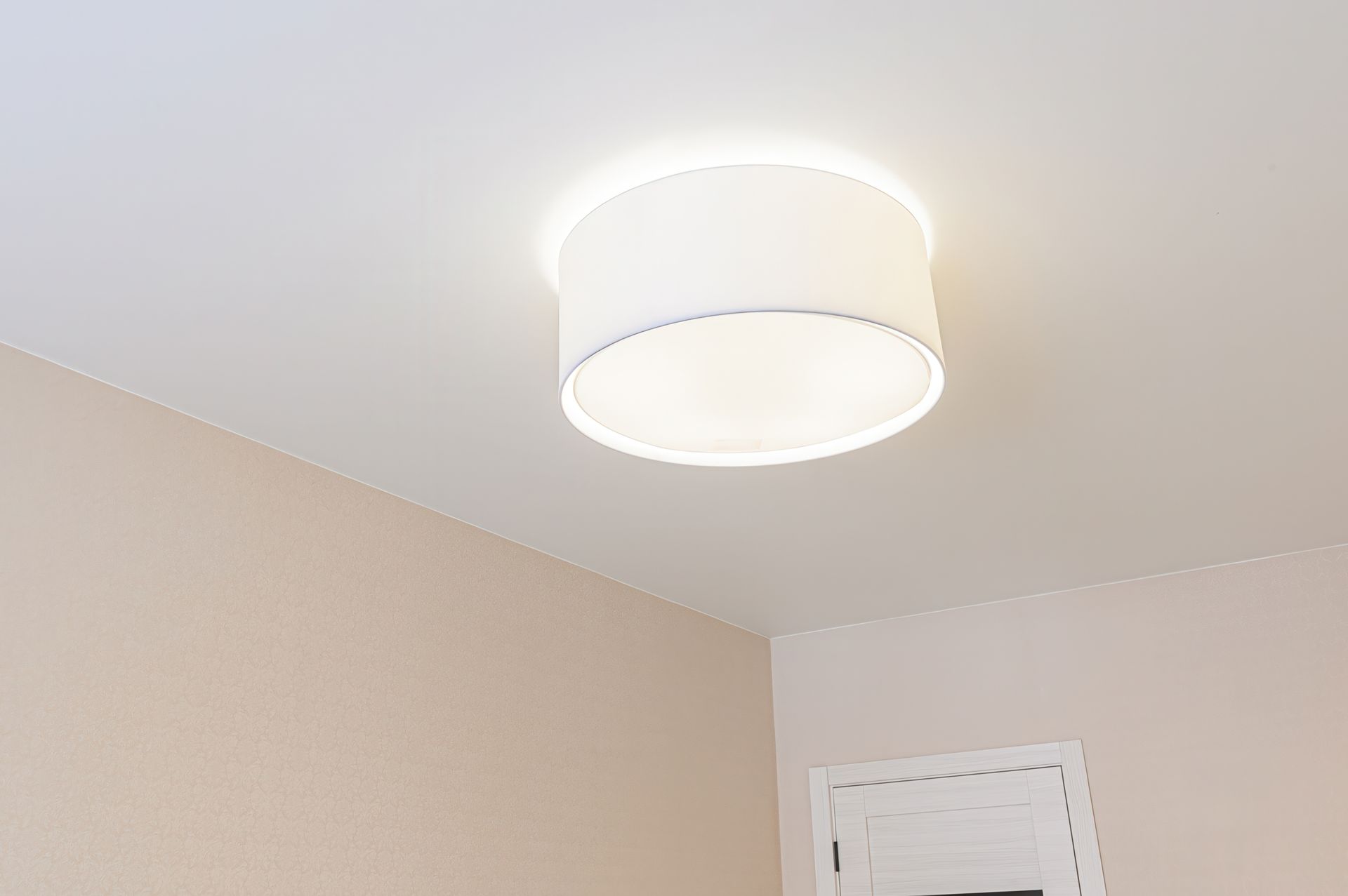 Ceiling light fixture on a beige room ceiling near a window