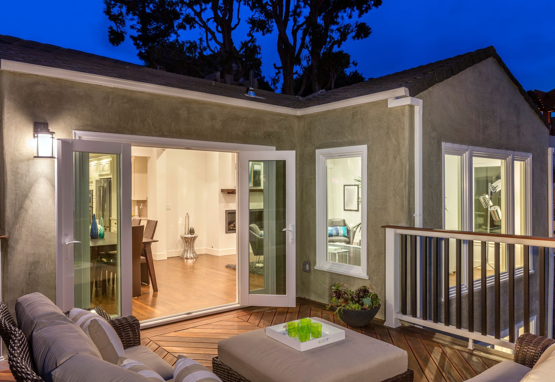 Modern patio with open glass doors, warm indoor lighting, and outdoor seating at dusk