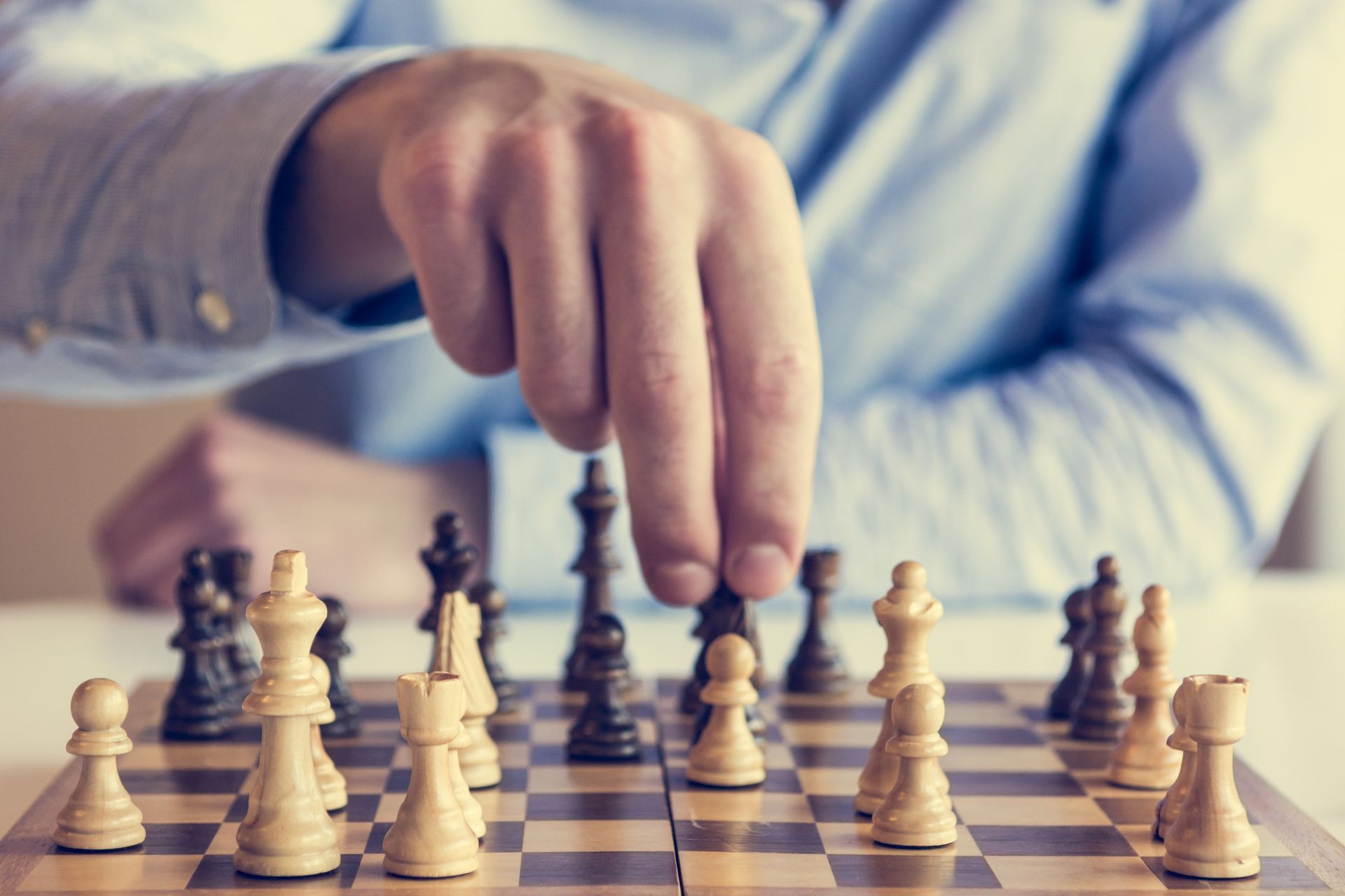 Hand moving a chess piece over a chessboard with white and black pieces