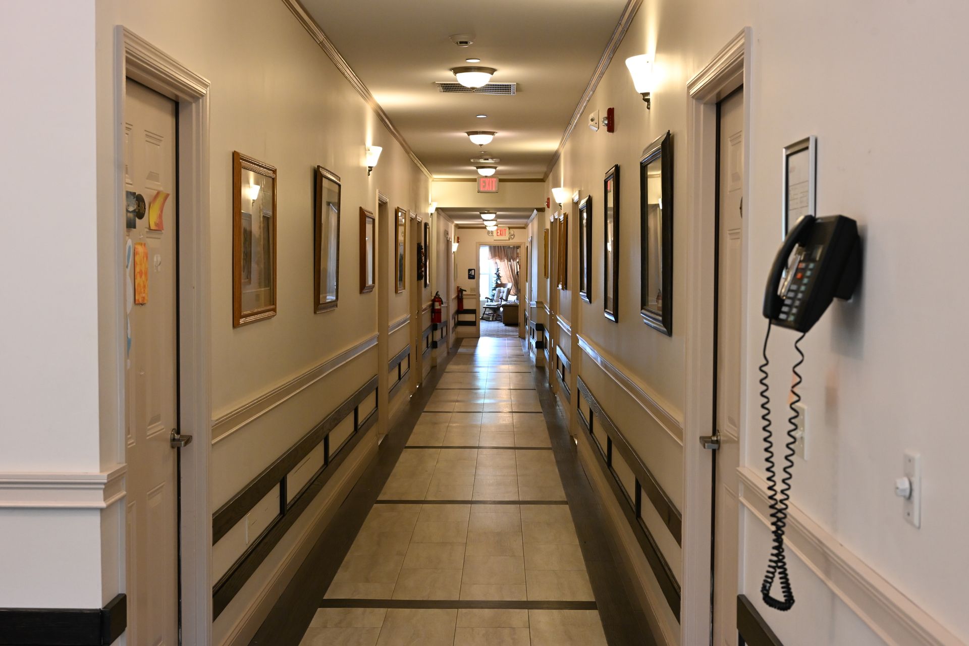 Long hallway with doors, framed art, and a wall phone.
