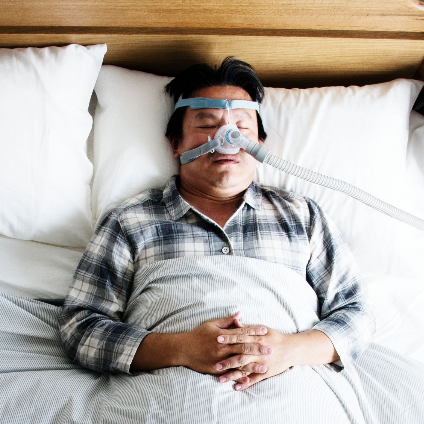 Man in bed wearing a CPAP mask, sleeping.