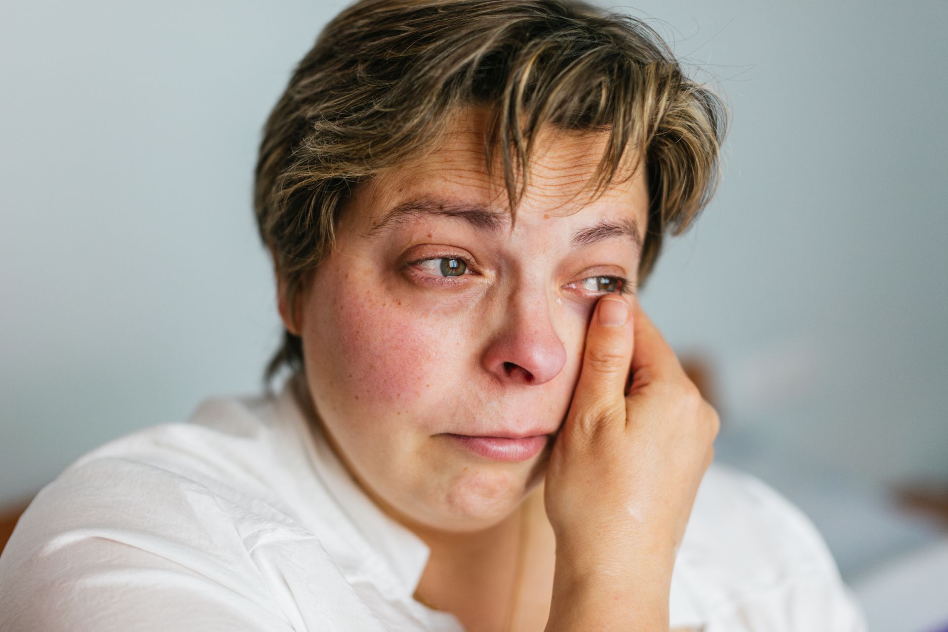 Person looking upset and exhausted against a plain background