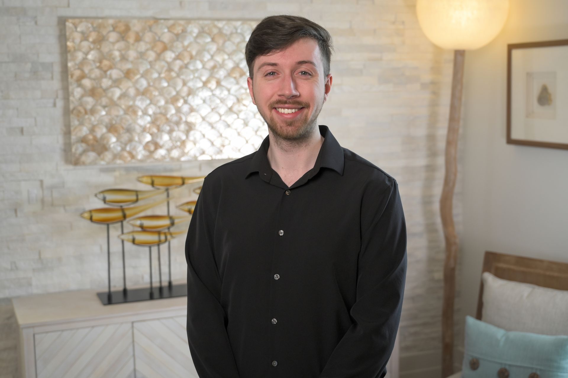A man in a black shirt is standing in a living room.