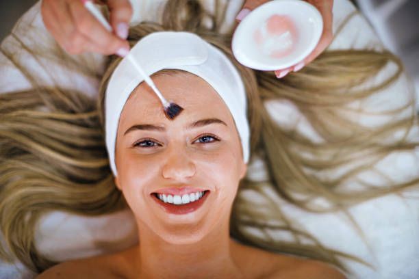 A woman is smiling while getting a facial treatment at a spa.