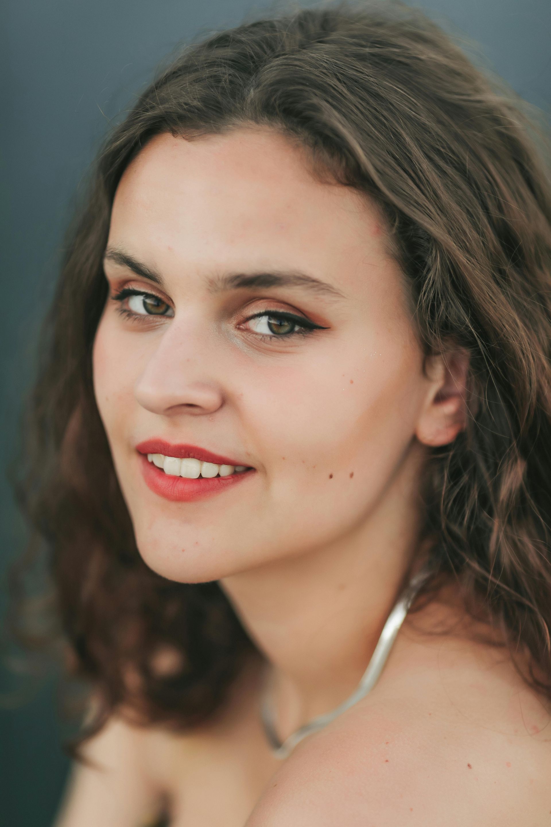 A close up of a woman 's face wearing a necklace and smiling.