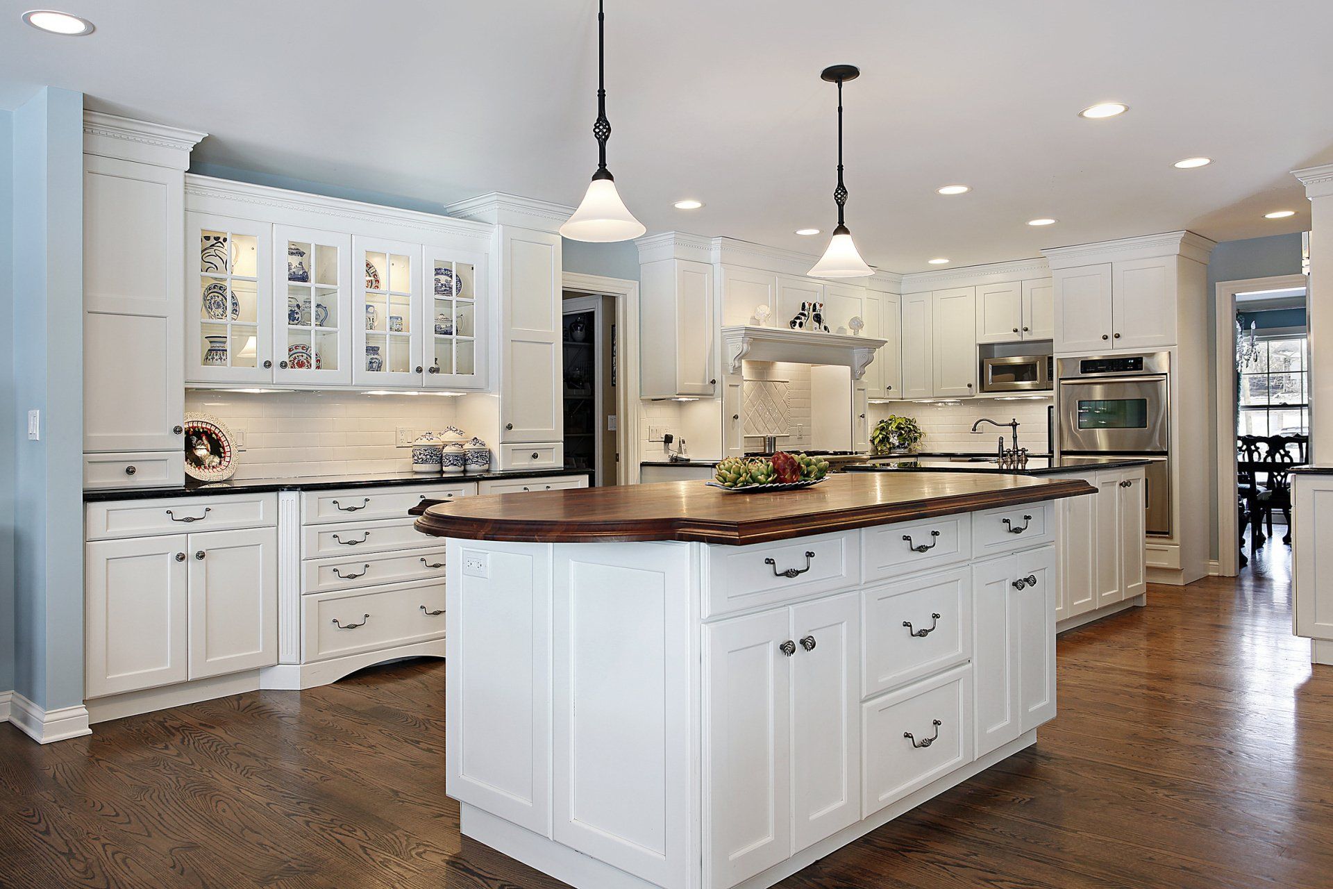 A kitchen with white cabinets and a large island in the middle