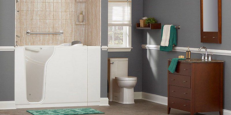 A bathroom with a walk in tub , toilet , sink and mirror.