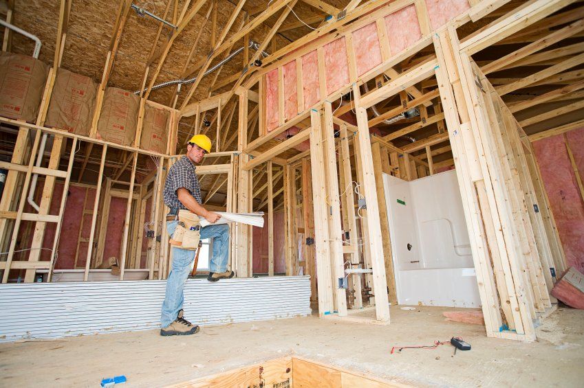 A construction worker is standing in the middle of a house under construction.