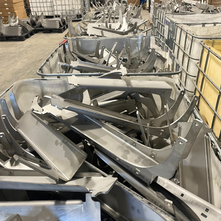 Metal scrap parts overflowing in large containers. Industrial setting.