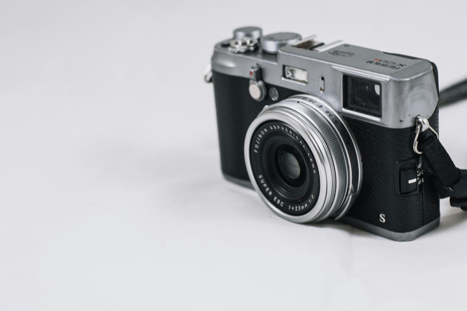 A black and silver camera is sitting on a white surface.