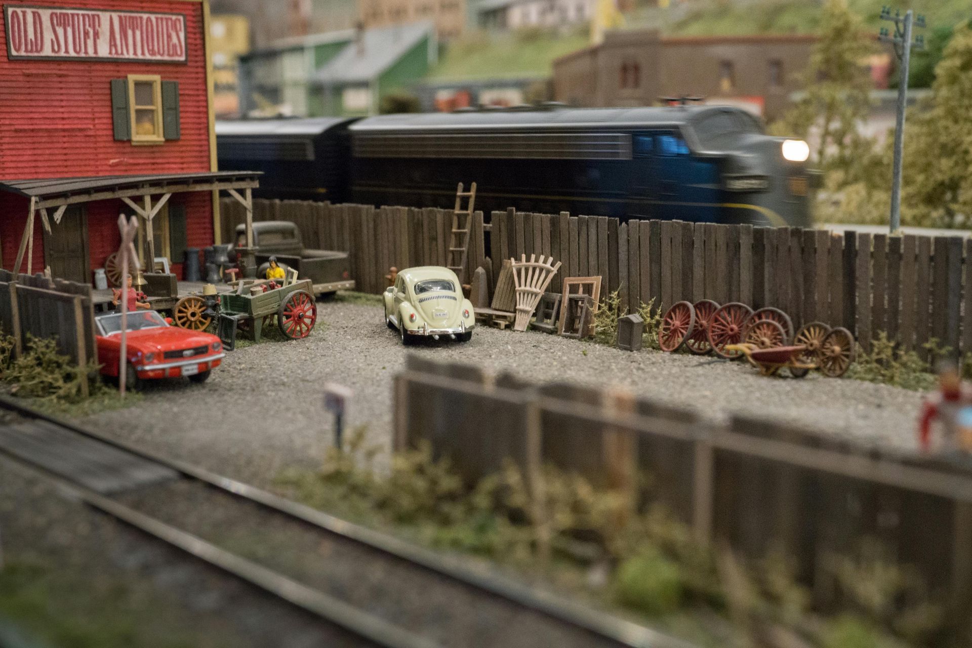 A train is going down the tracks next to a model train set.