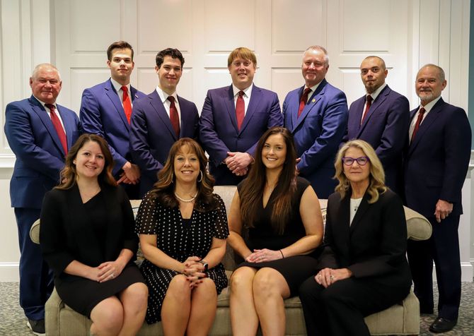A group of eleven people in formal business attire posed for a professional portrait in an office setting.