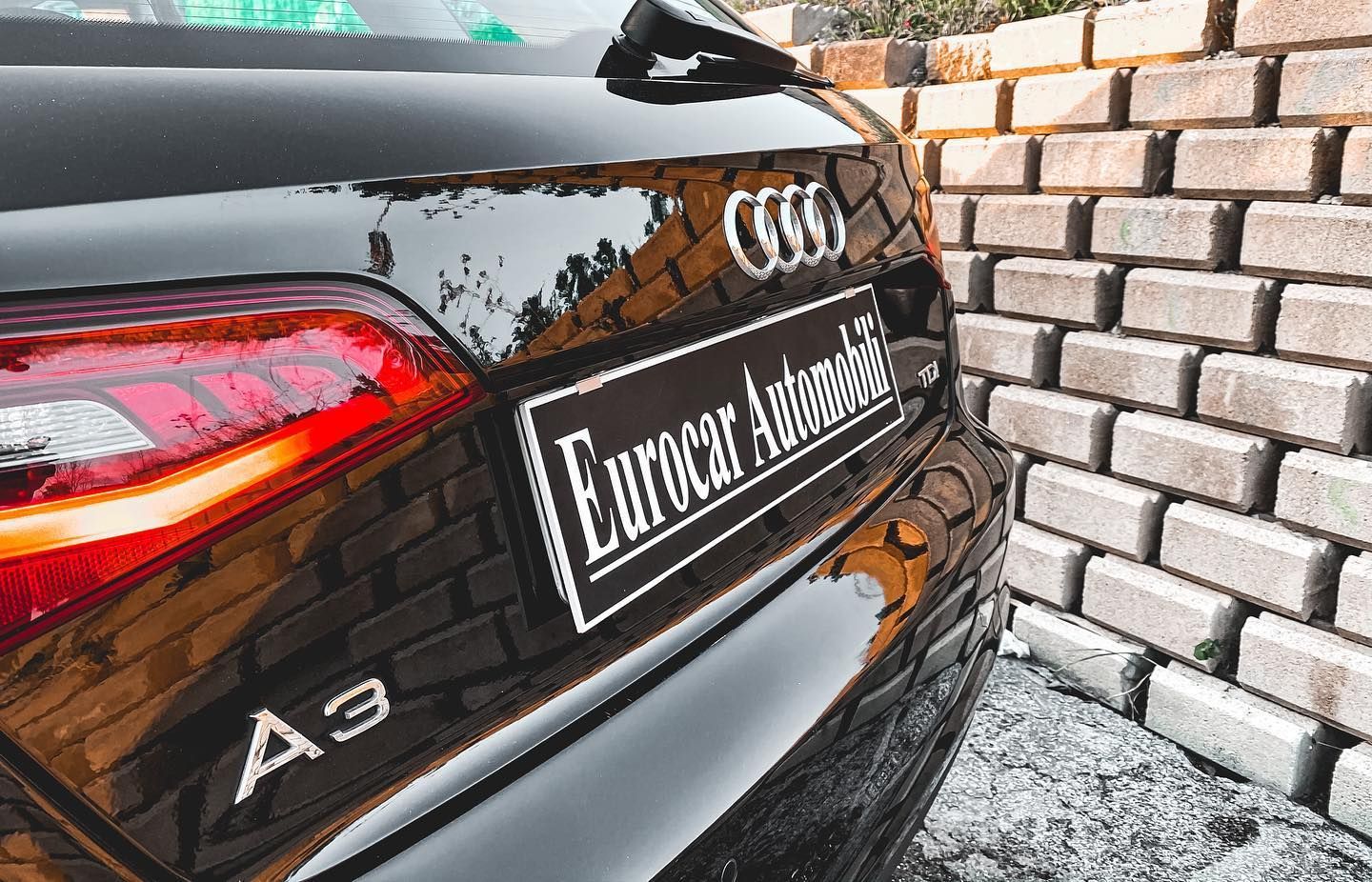un'audi a3 nera è parcheggiata davanti a un muro di mattoni.