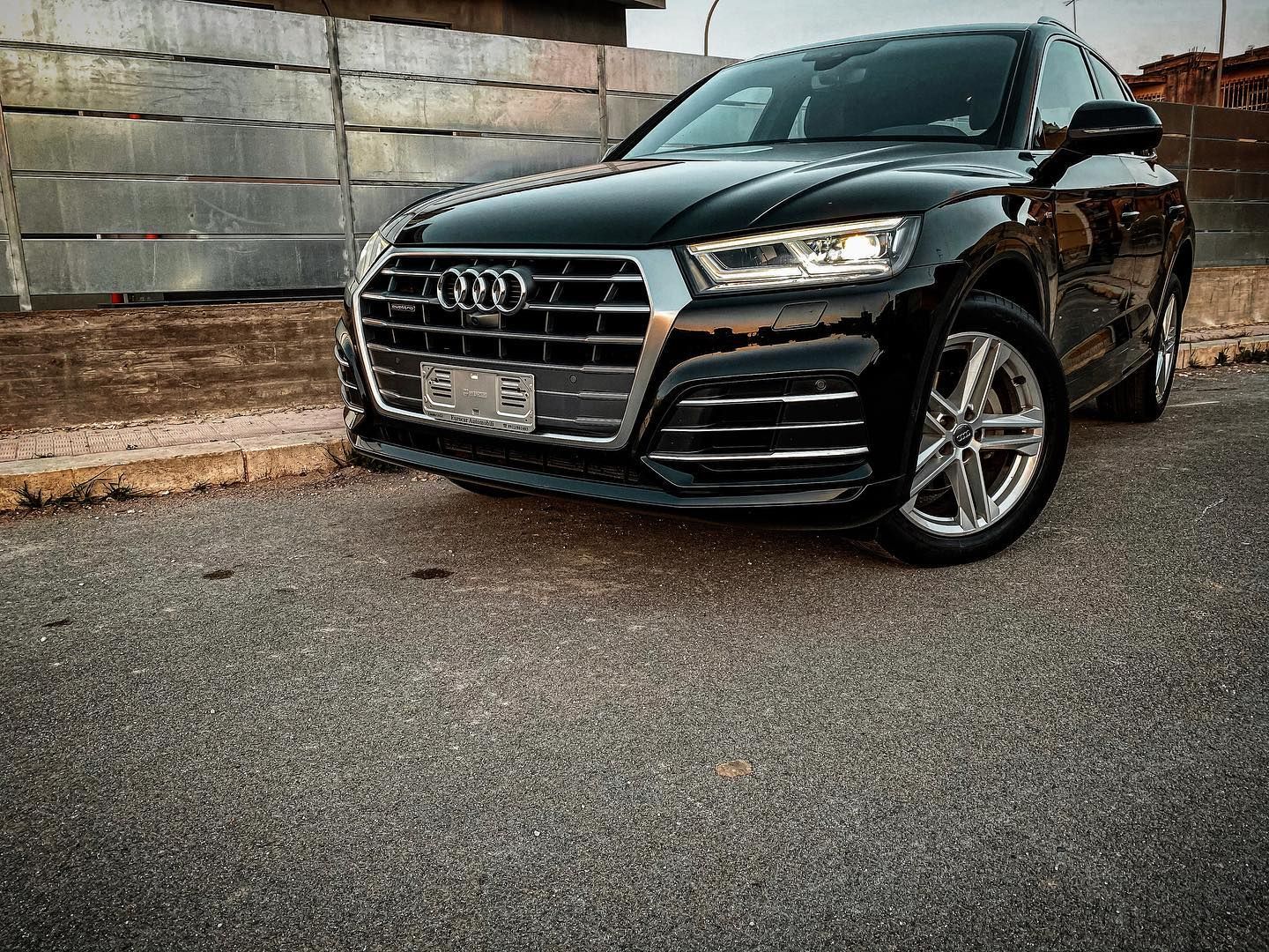 un'audi q5 nera è parcheggiata davanti a una recinzione.
