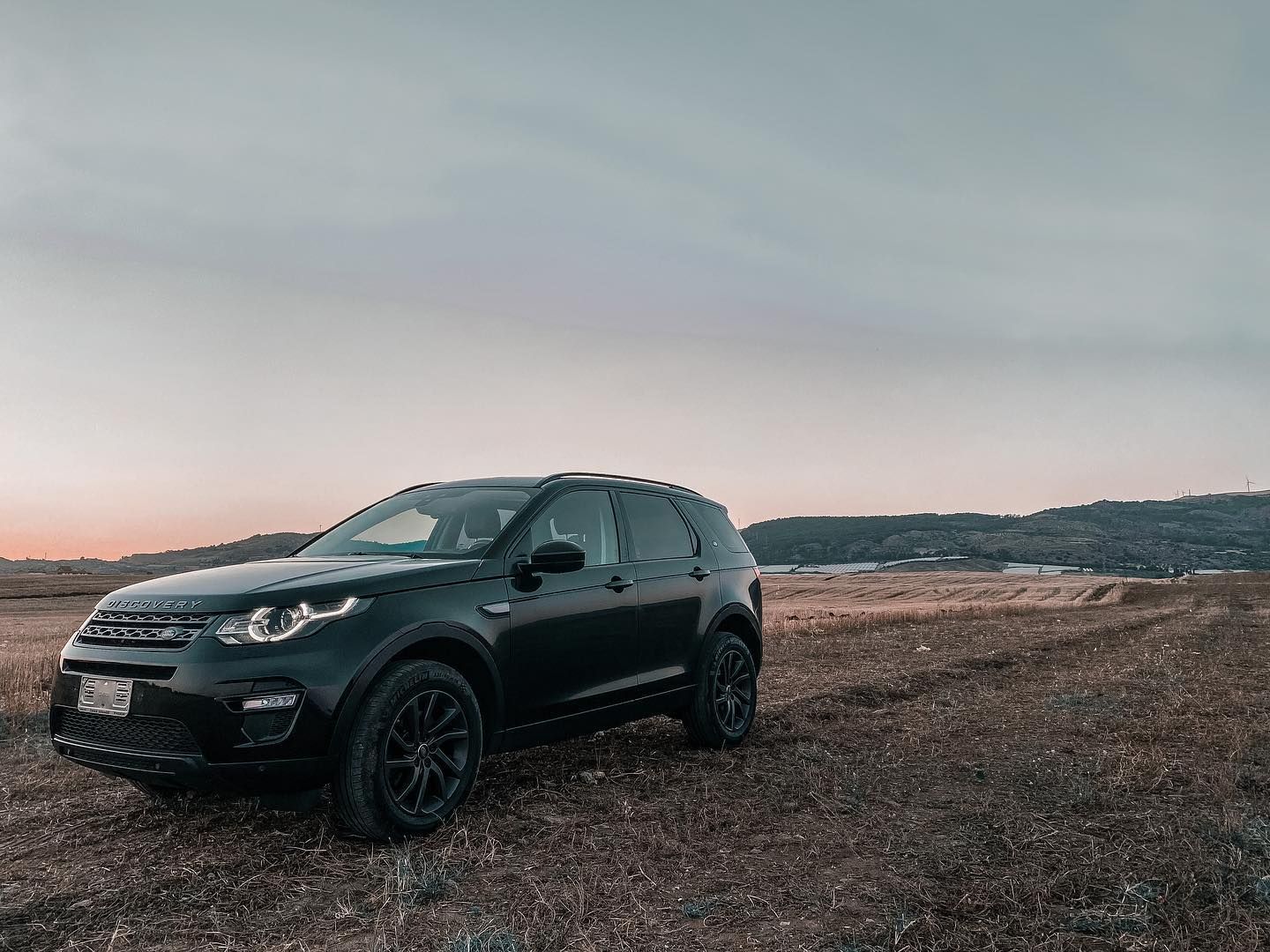 una land rover discovery nera è parcheggiata in un campo.