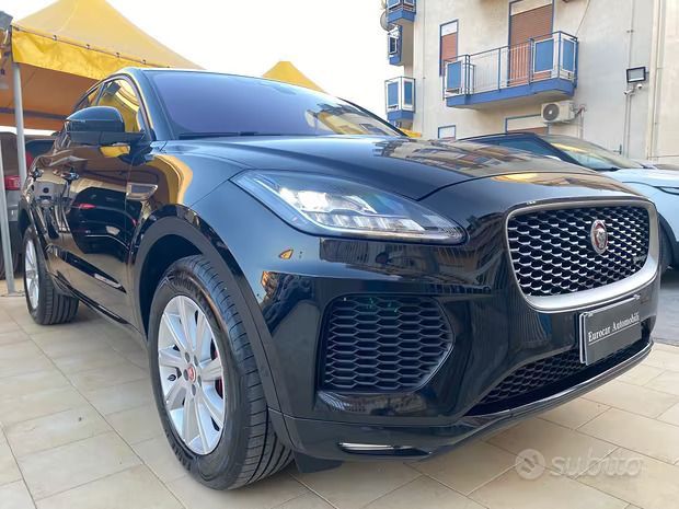 un'auto nera è parcheggiata sul lato di una strada vicino all'oceano al tramonto.