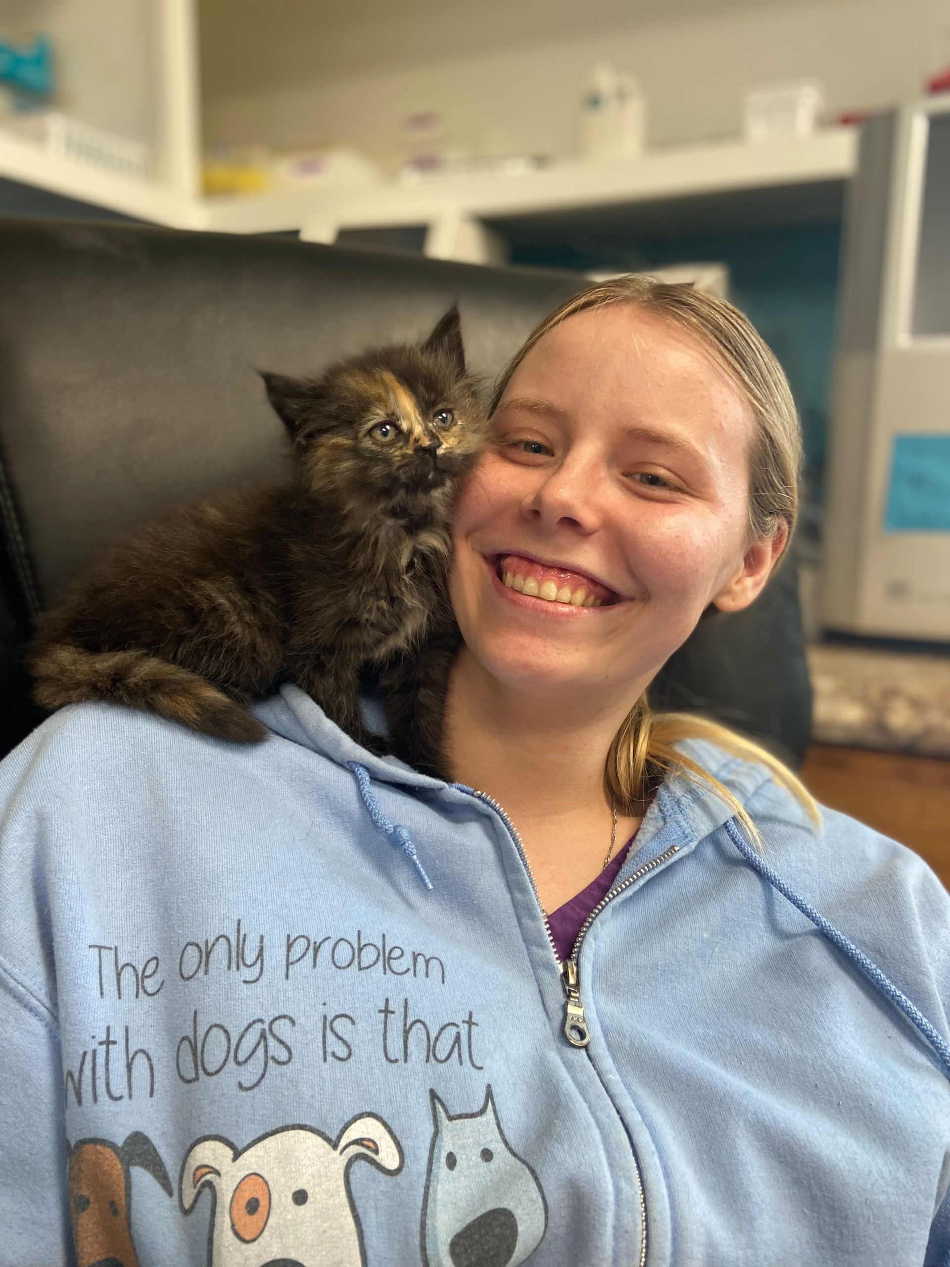 Katrina is holding a cat on her shoulder.