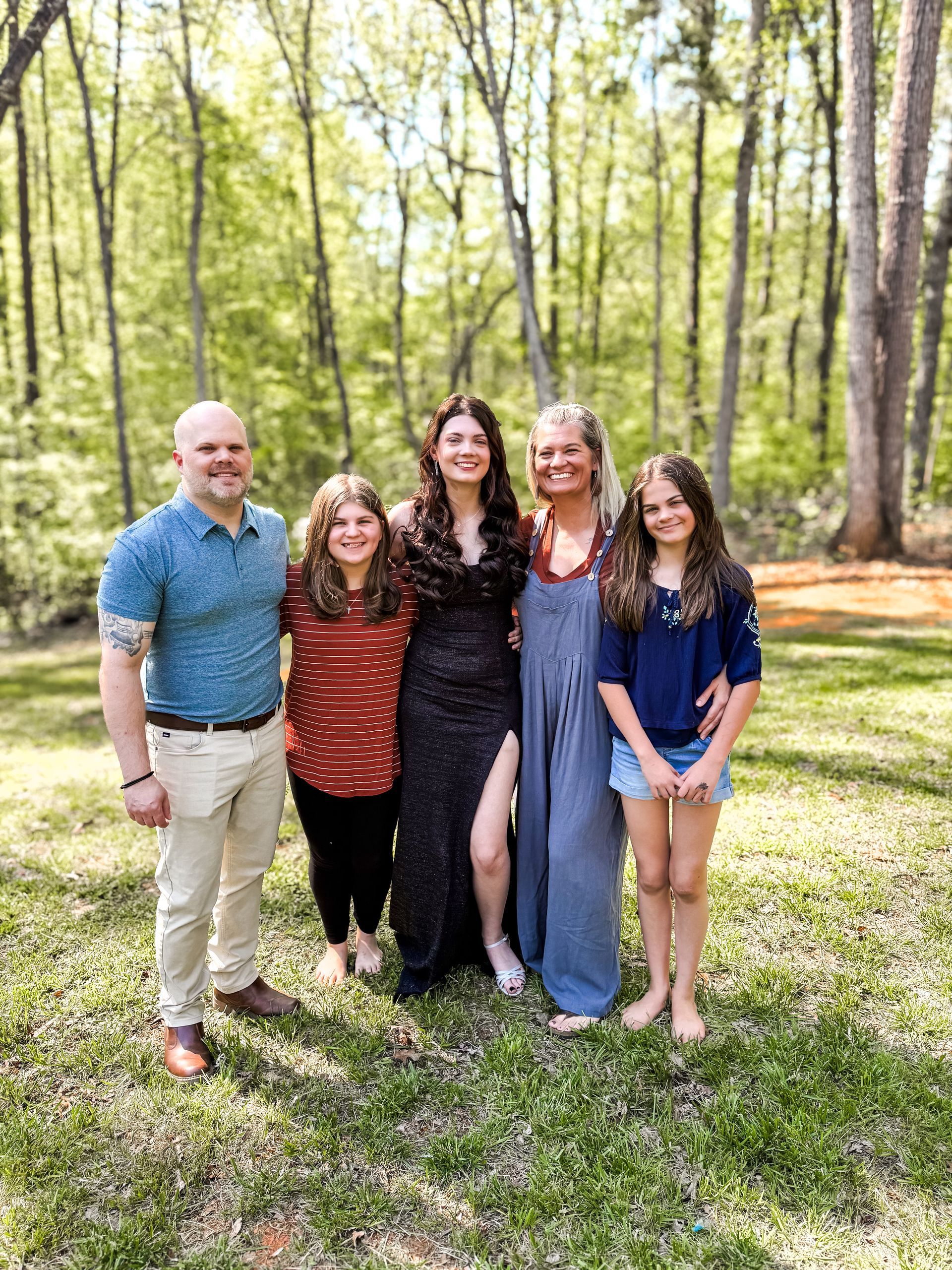 A family is posing for a picture in the woods.