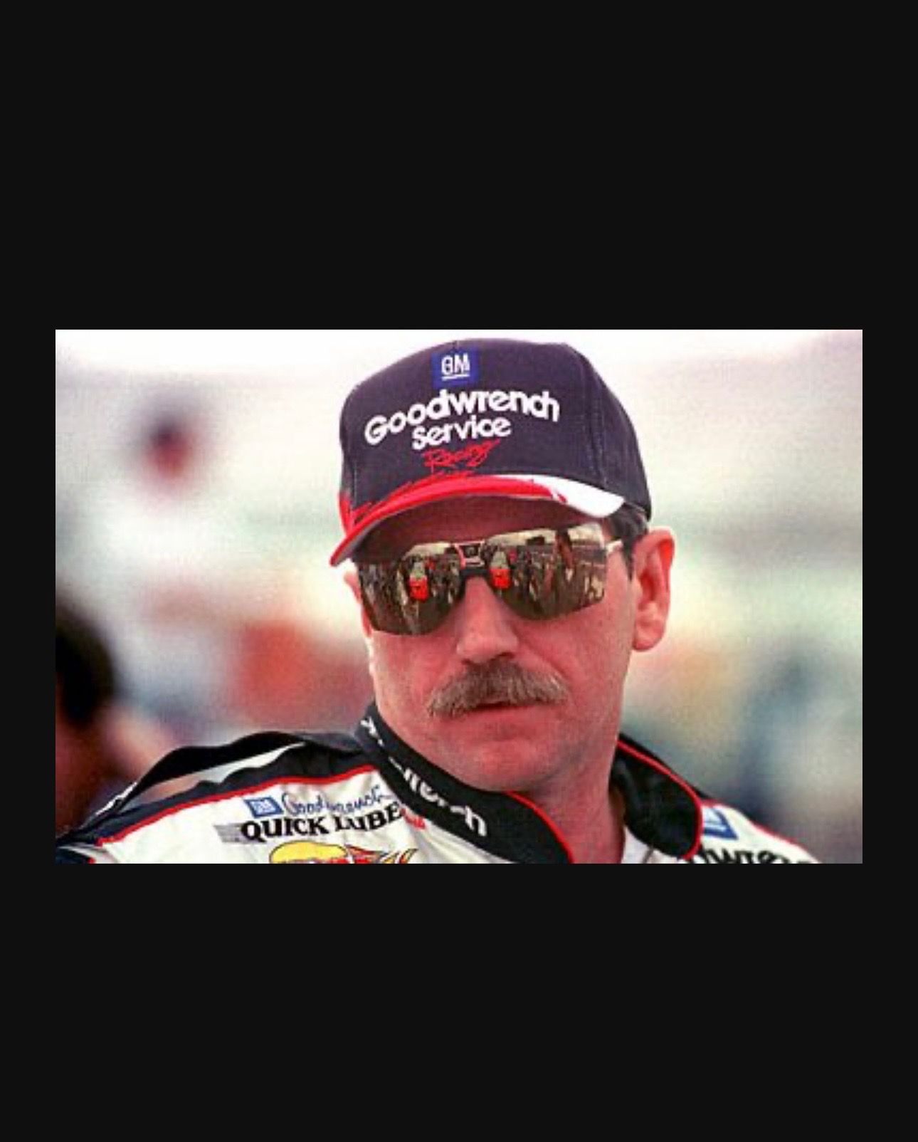 A man wearing a goodwrench service hat and sunglasses