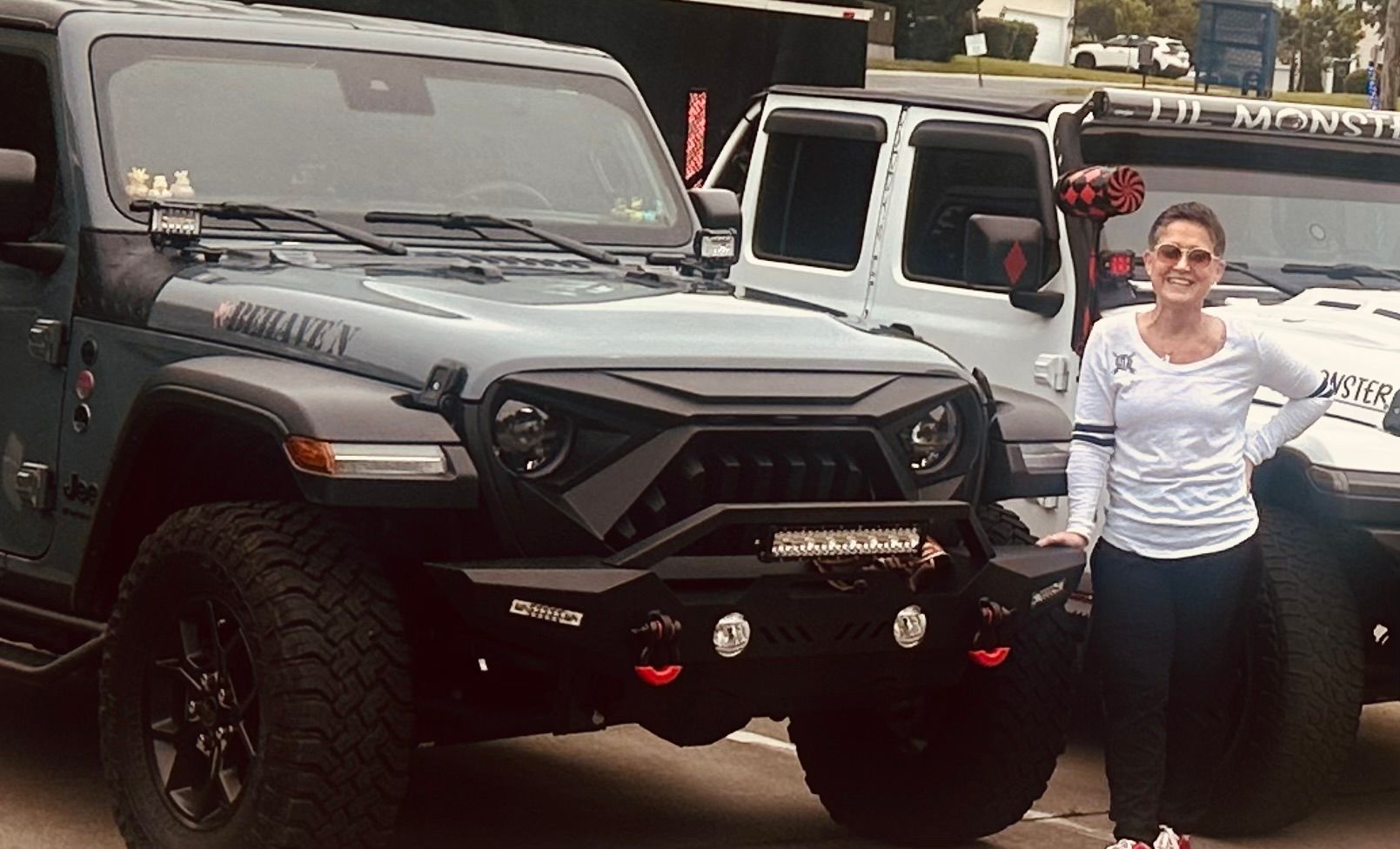 Jody is standing next to a jeep in a parking lot.