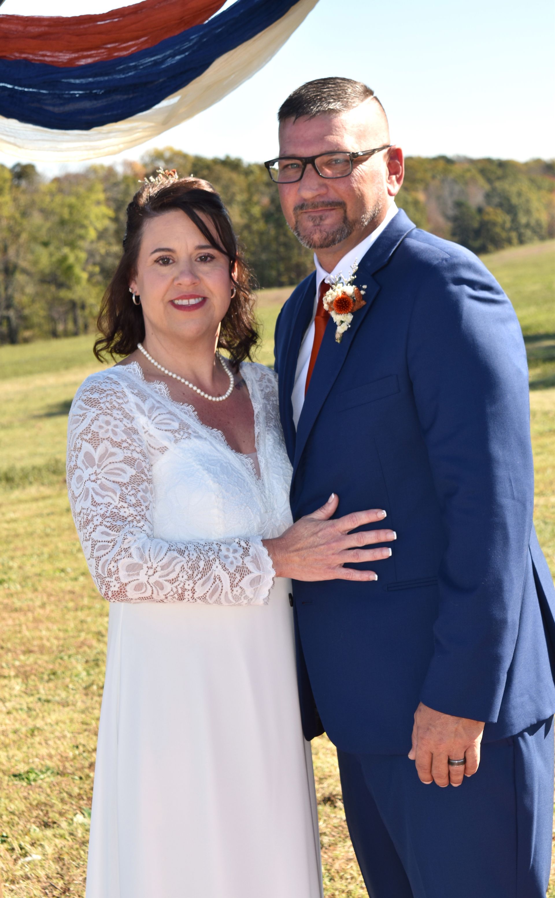Allison and groom are posing for a picture in a field.