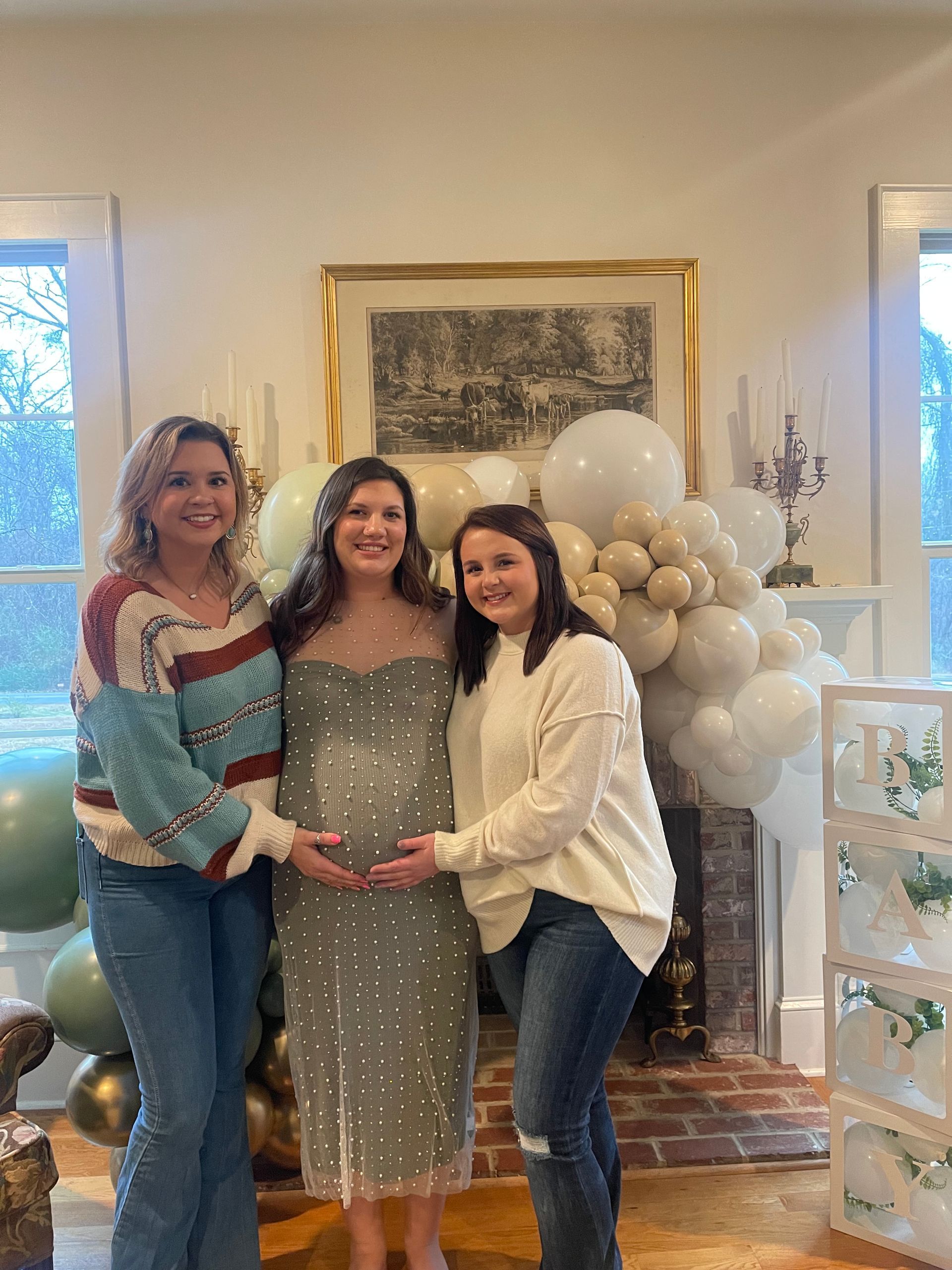 Three women are posing for a picture with a pregnant woman in a room.