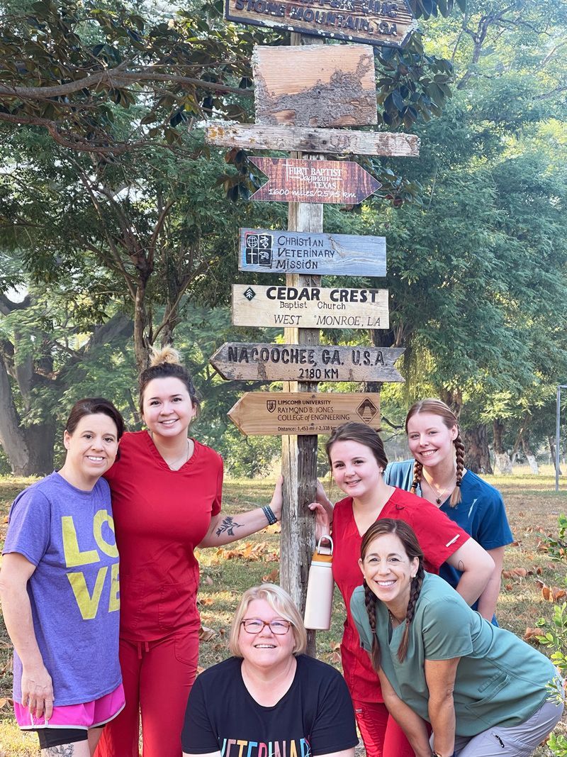 The Clover Vet team members are posing for a picture in front of a sign in Honduras