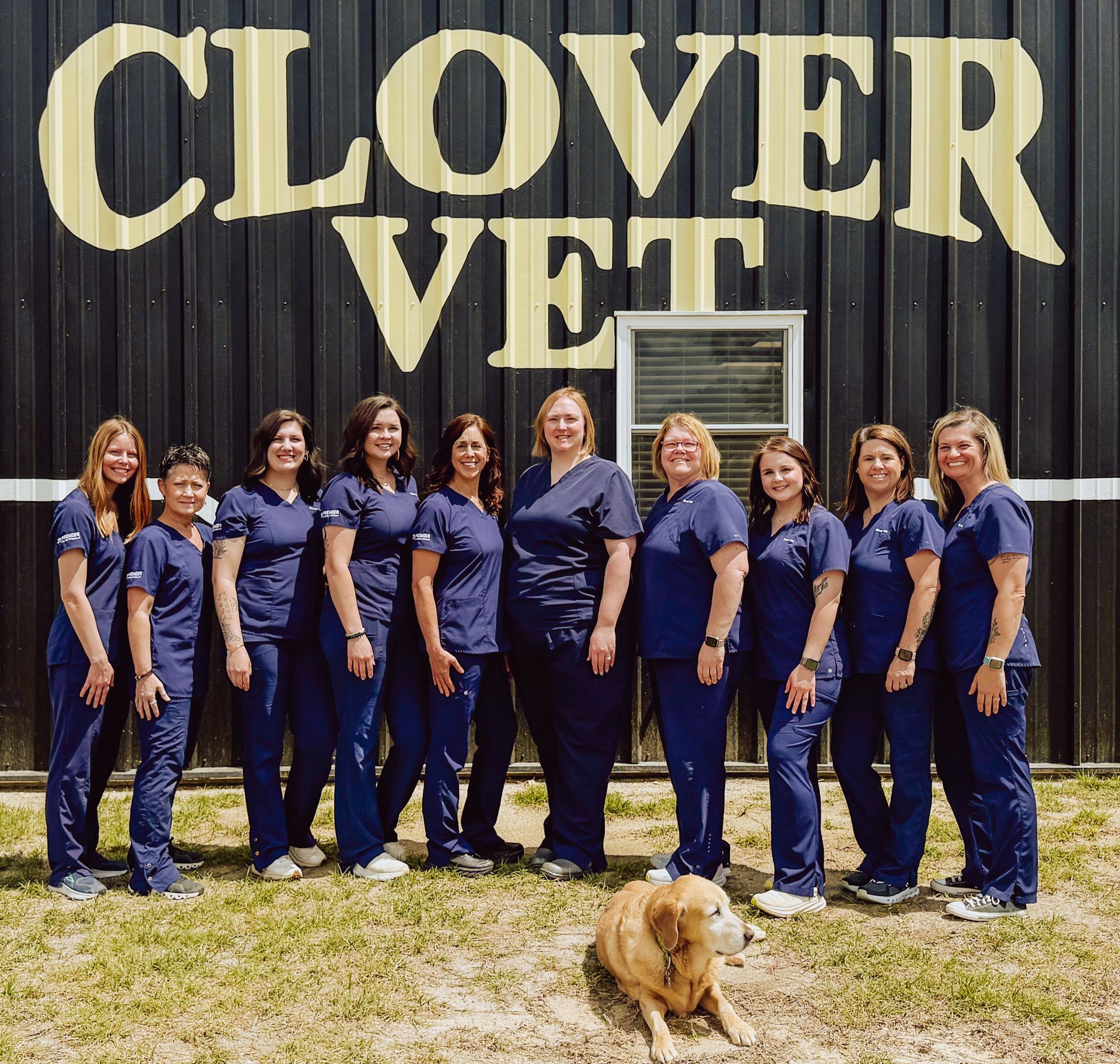 A group of women standing in front of a clover vet sign