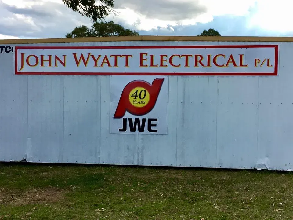 A sign for john wyatt electrical p / l is painted on a white wall
