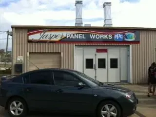 A car is parked in front of a jaspe panel works building
