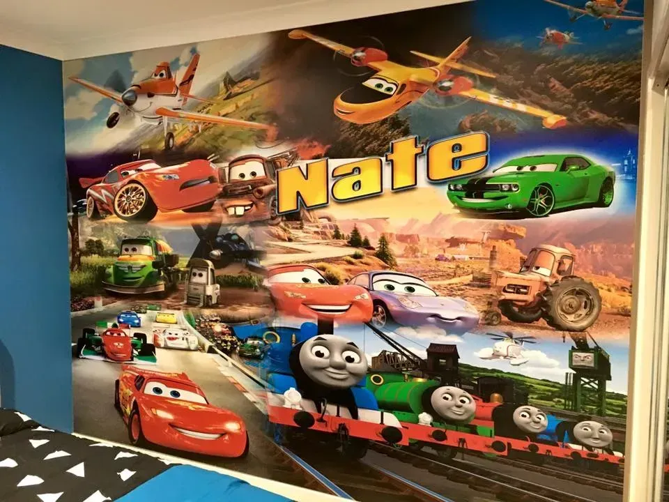 A wall with a picture of cars and thomas the tank engine on it.