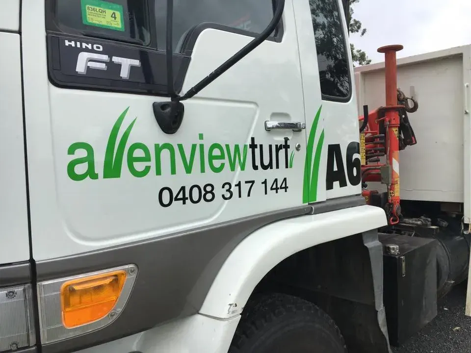 A white truck with green letters that say allenview turf
