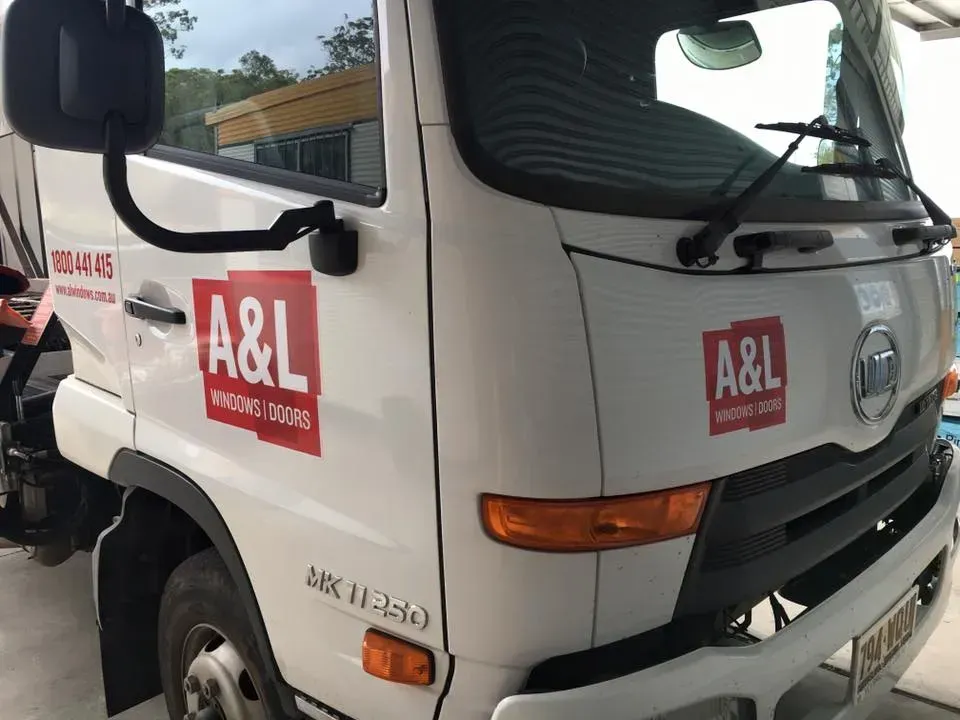 A white a & l truck is parked on the side of the road.