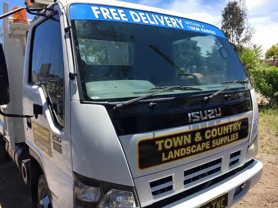 A white truck with a blue banner on the windshield that says free delivery