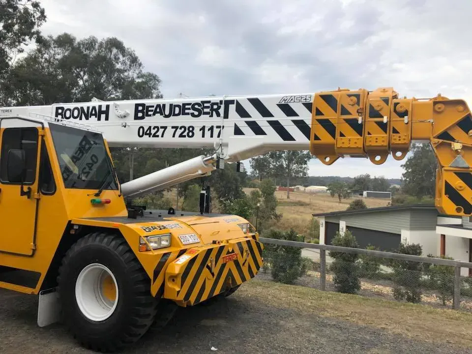 A yellow truck with a crane attached to it is parked on the side of the road.