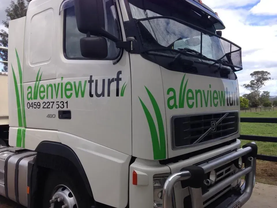 A white truck with green writing that says allenview turf