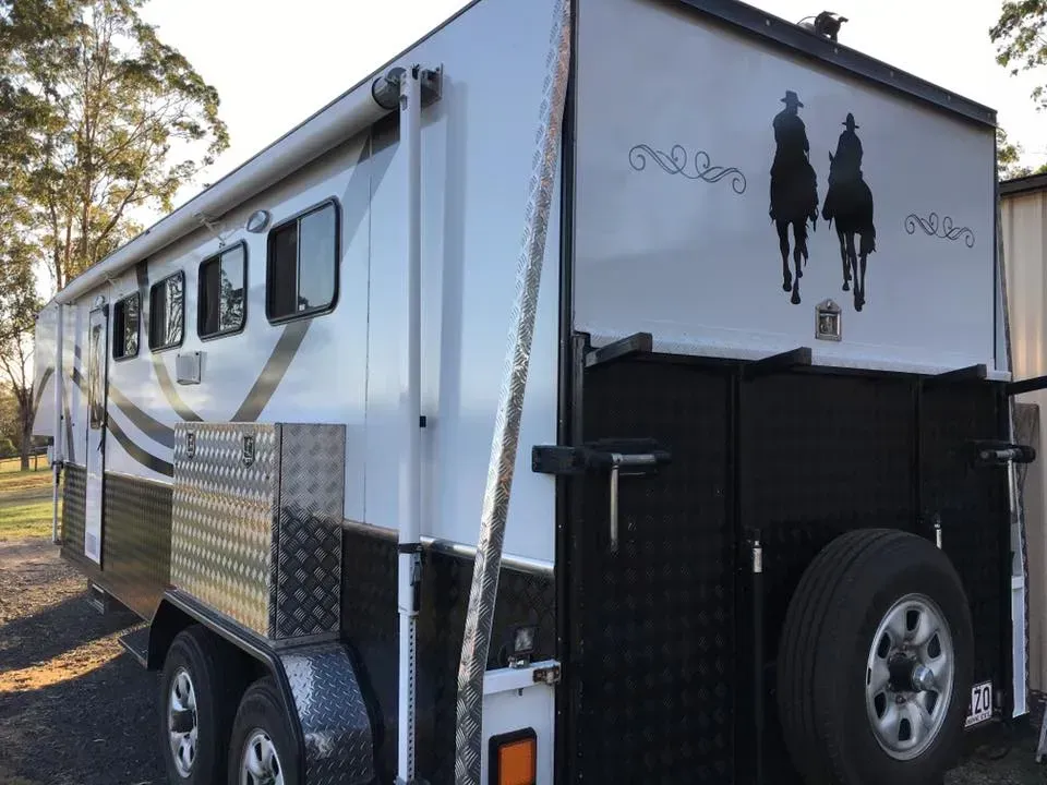 A white trailer with two horses on the side