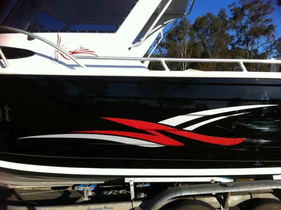 A black and white boat with red and white stripes on the side