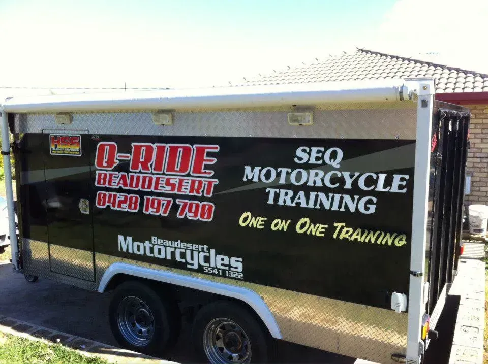 A motorcycle training trailer is parked in front of a house