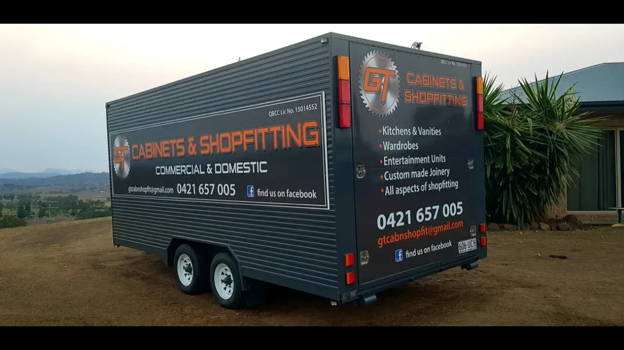 A black trailer is parked in front of a house.